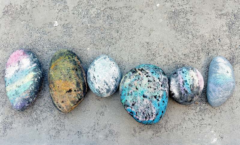 Hand painting a smooth river rock with vibrant acrylics: sunflower design, brush in hand, natural light
